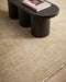 Corbett Floor Rug in Honey, close up under a dark timber bench with books, showing the fringed edge
