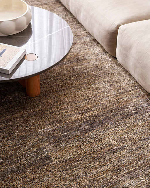 Fairbanks Floor Rug in Fossil, seen from above beside a stone coffee table and cream sofa