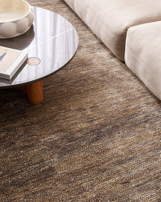 Fairbanks Floor Rug in Fossil, seen from above beside a stone coffee table and cream sofa