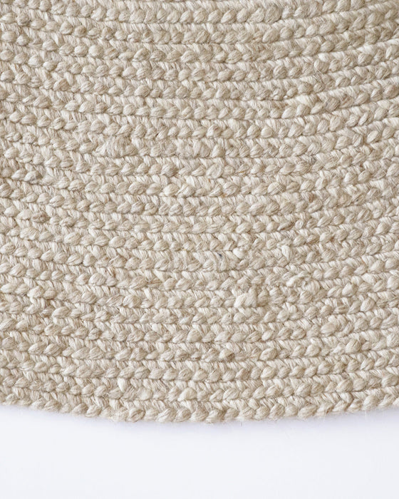 Tairua Round Floor Rug in Natural Straw, close-up of the curved edge and wool and viscose weave