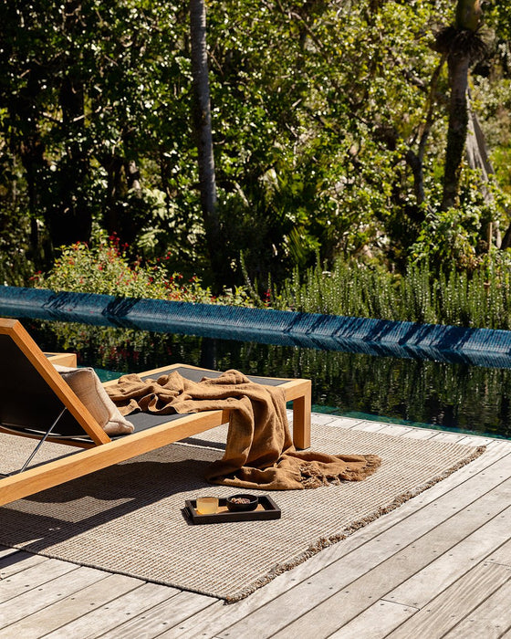 Rhodes Floor Rug in Teak, on a poolside timber deck with a teak sun lounger and tray
