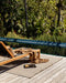 Rhodes Floor Rug in Teak, on a poolside timber deck with a teak sun lounger and tray