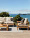 Rhodes Floor Rug in Slate, on a timber deck overlooking the sea with teak outdoor seating