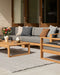 Rhodes Floor Rug in Slate, on a patio with a grey outdoor sofa and teak coffee table