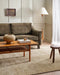 Fairbanks Floor Rug in Limestone, styled in a living room with an olive sofa and timber coffee table