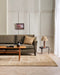 Fairbanks Floor Rug in Sand, in a panelled living room with an olive sofa and timber coffee table