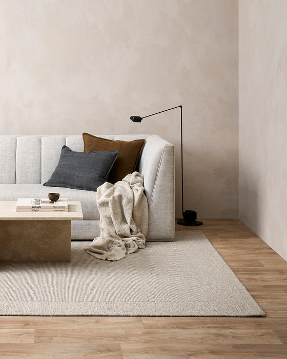 Vermont Floor Rug in Driftwood, in a living room with a white sofa, cushions and stone coffee table